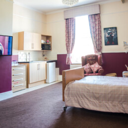QH carousel image displaying a residents room which contains a flat screen tv